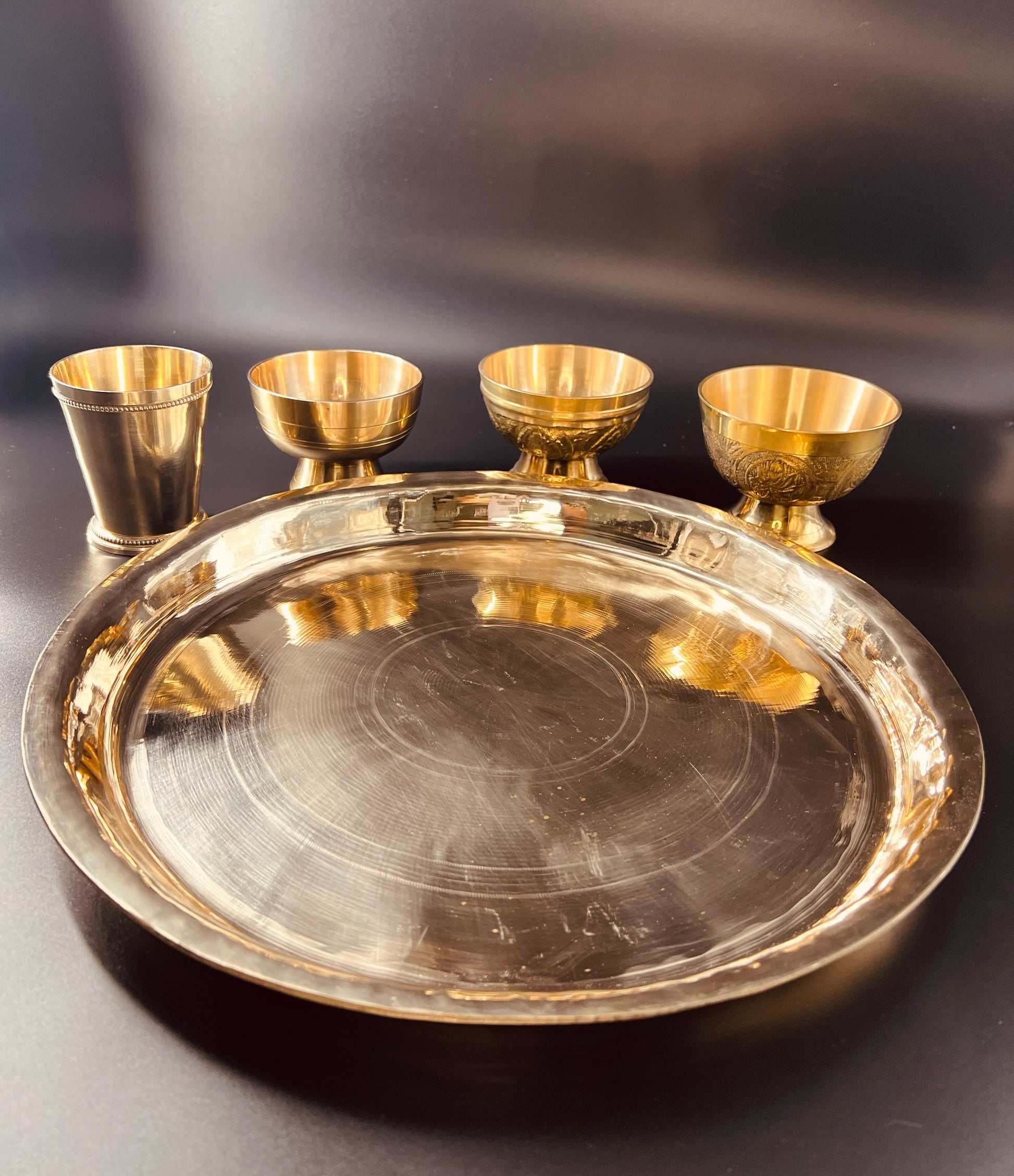 A 13" bronze plate with three bronze bowl and a bronze glass.